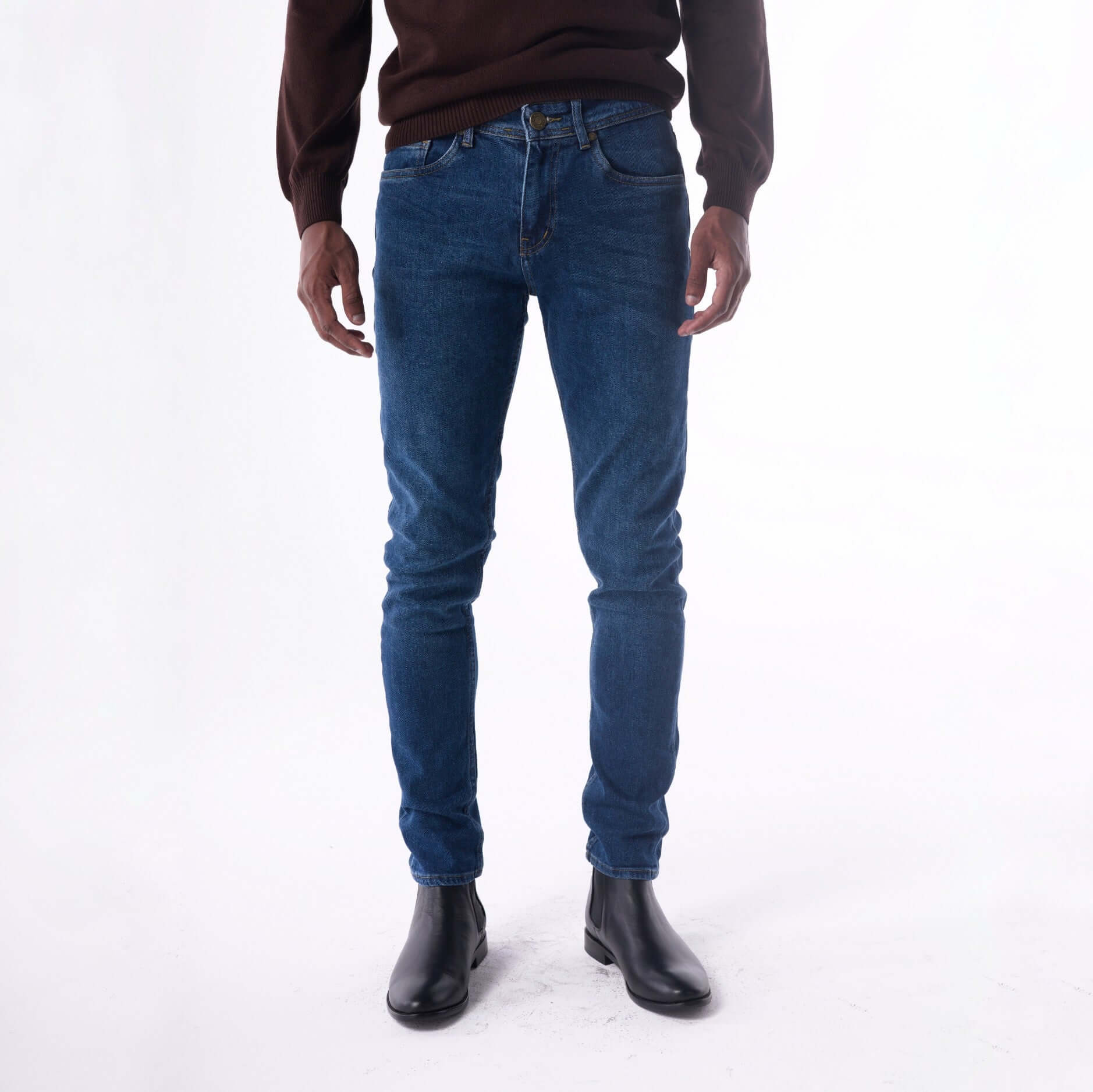 Person wearing blue jeans and black shoes on a white background