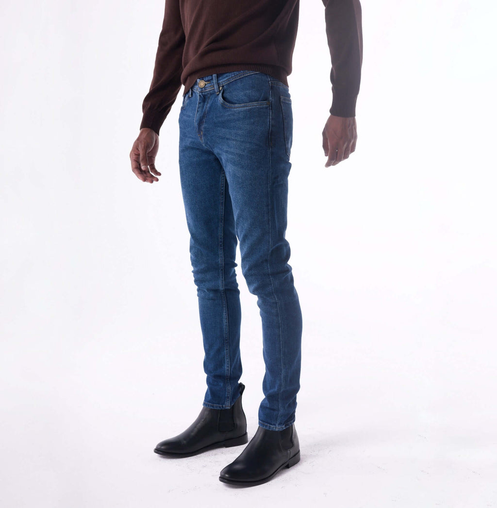 Person wearing blue jeans and black shoes on a white background