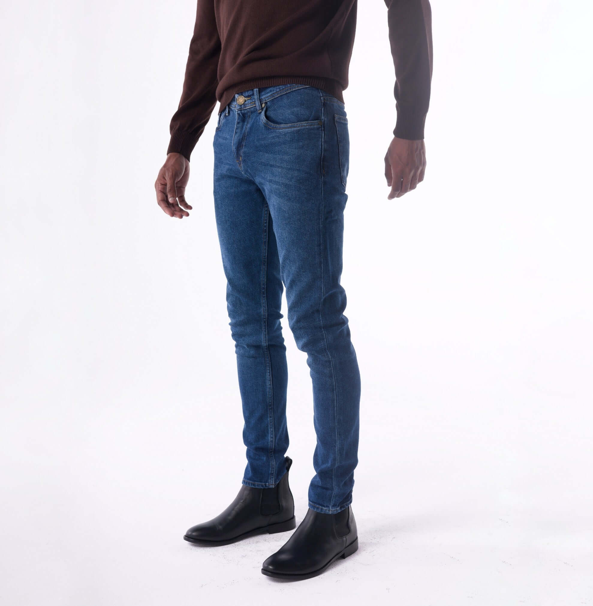 Person wearing blue jeans and black shoes on a white background