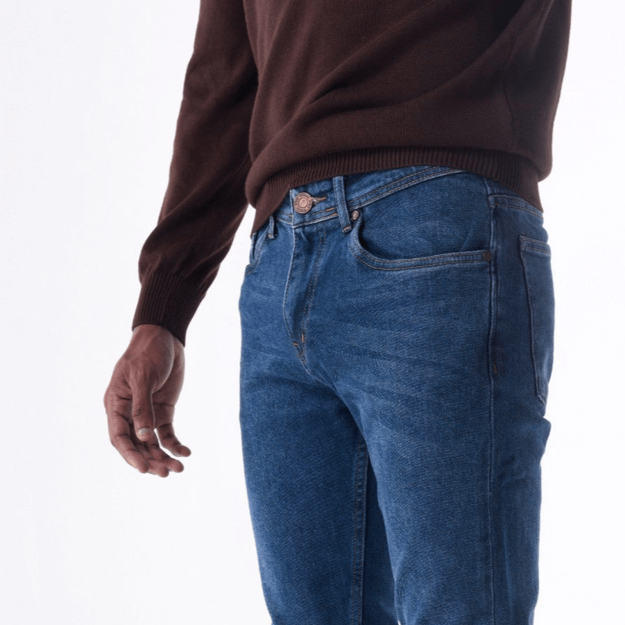 Man wearing SOLID stone washed slim jeans with a brown sweater, showcasing tailored fit and dark wash premium denim.