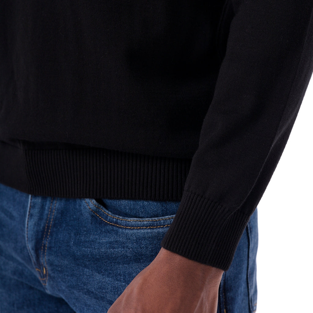 Person wearing a black sweater and blue jeans on a white background