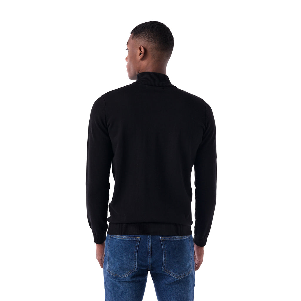 Man wearing a black turtleneck sweater and blue jeans on a white background