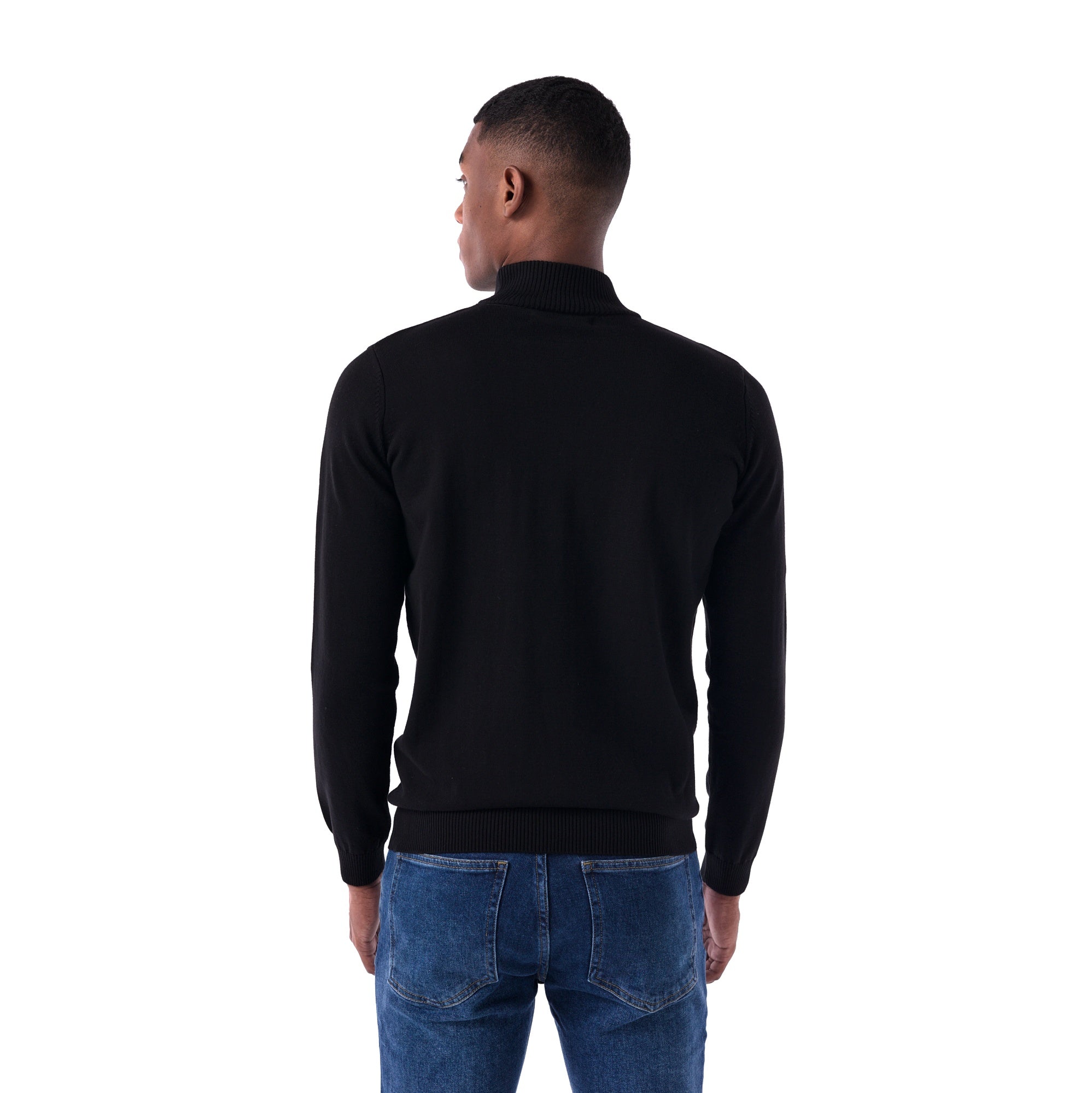 Man wearing a black turtleneck sweater and blue jeans on a white background