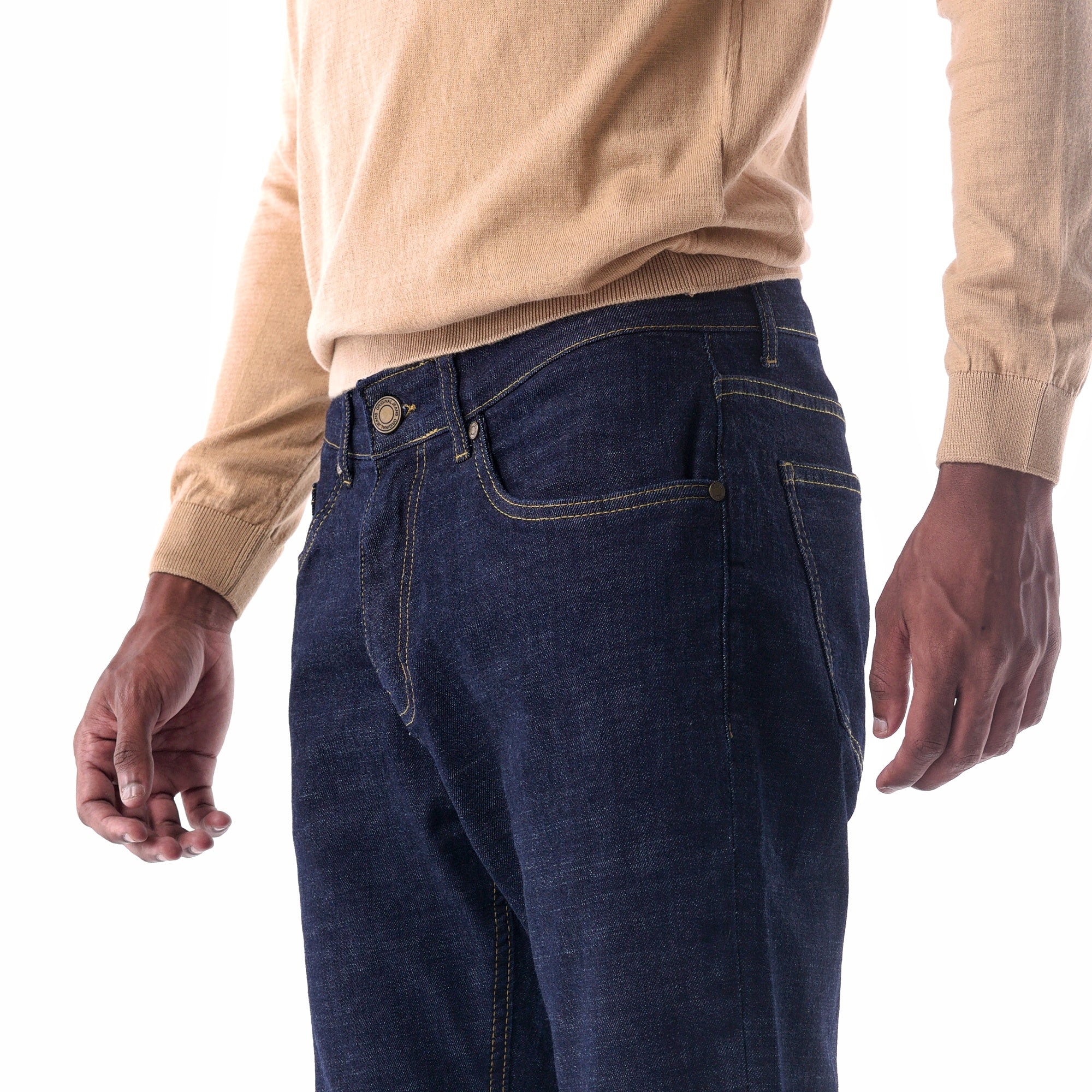 Person wearing dark blue jeans and a beige sweater on a white background