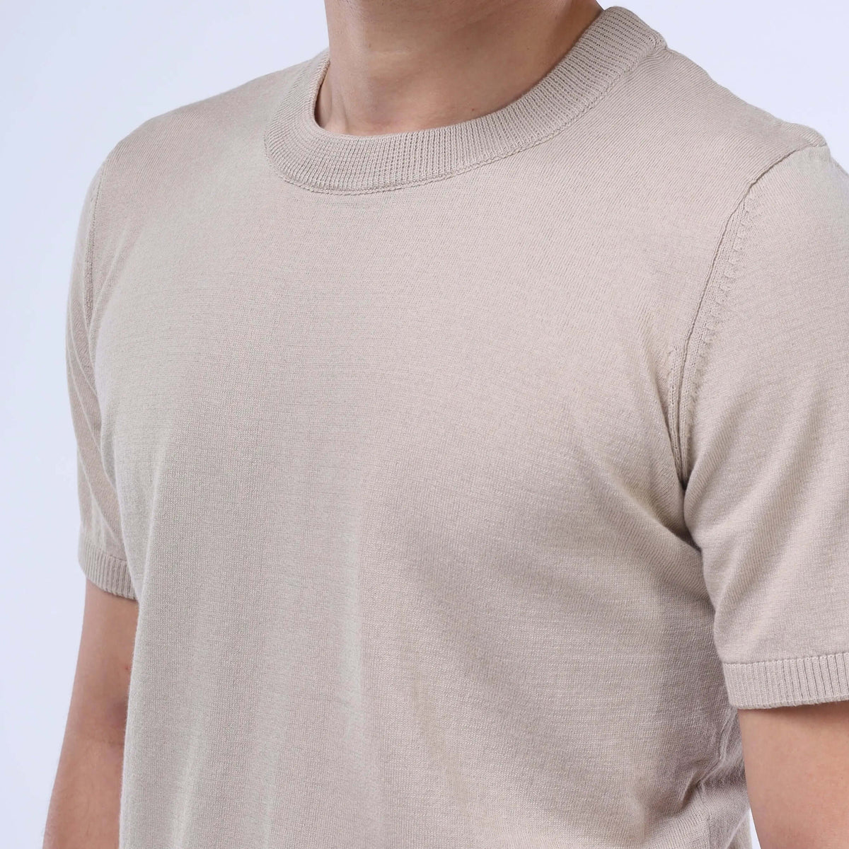 Close-up of a man wearing a solid beige CloudKnit Crew Tee made from soft Egyptian cotton.