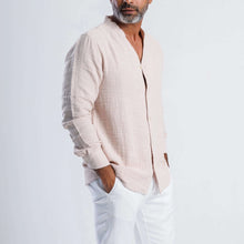 Load image into Gallery viewer, Man wearing a collarless linen blend summer shirt in soft pink, styled with white trousers and a relaxed pose.
