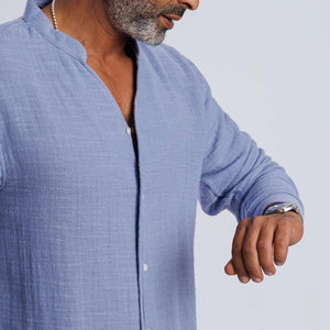 Man in collarless blue linen-blend shirt, showcasing casual summer style and versatility for layered looks.