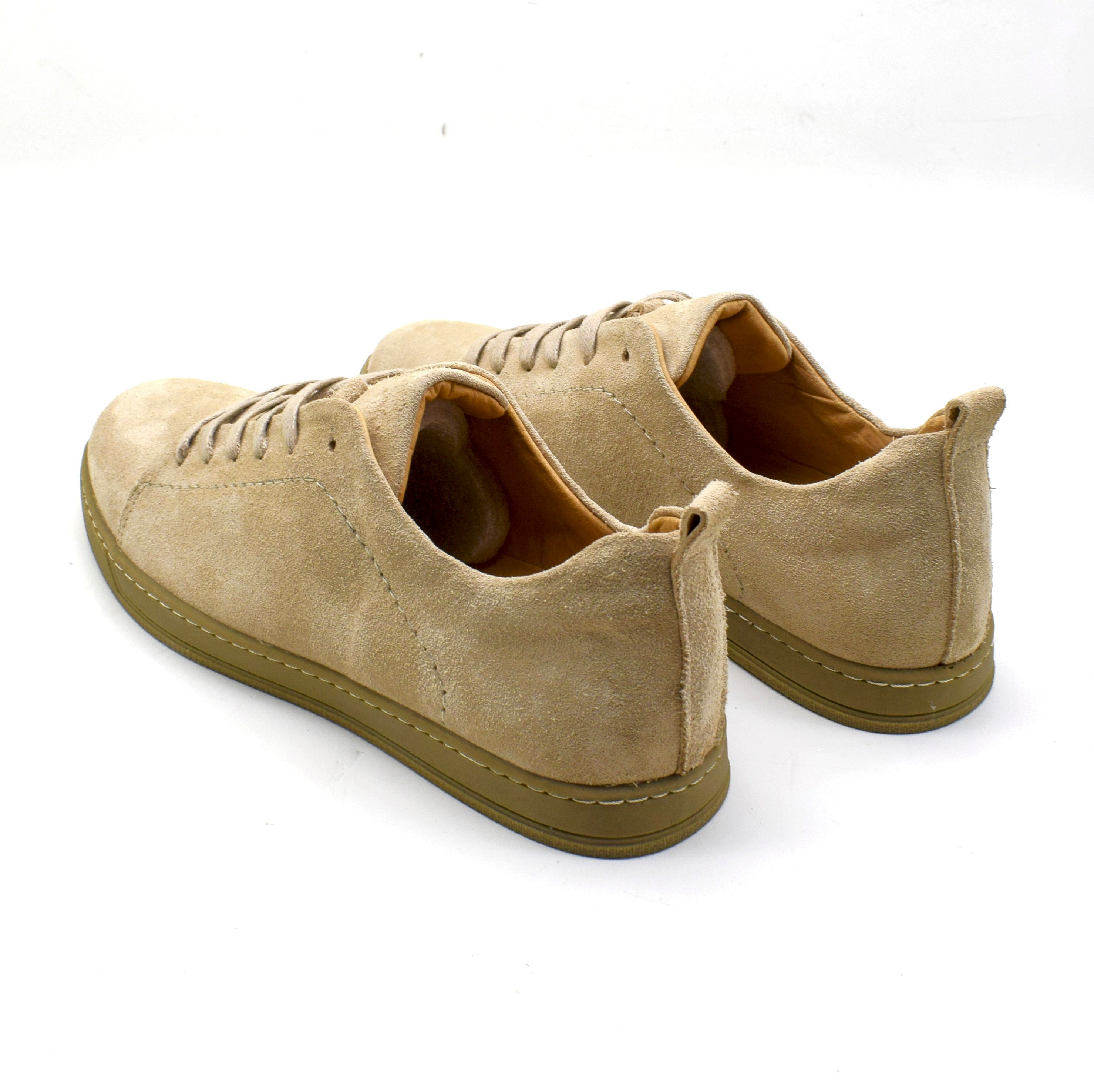 A pair of beige suede low-top sneakers with matching beige laces and olive-brown soles, photographed on a clean white background.