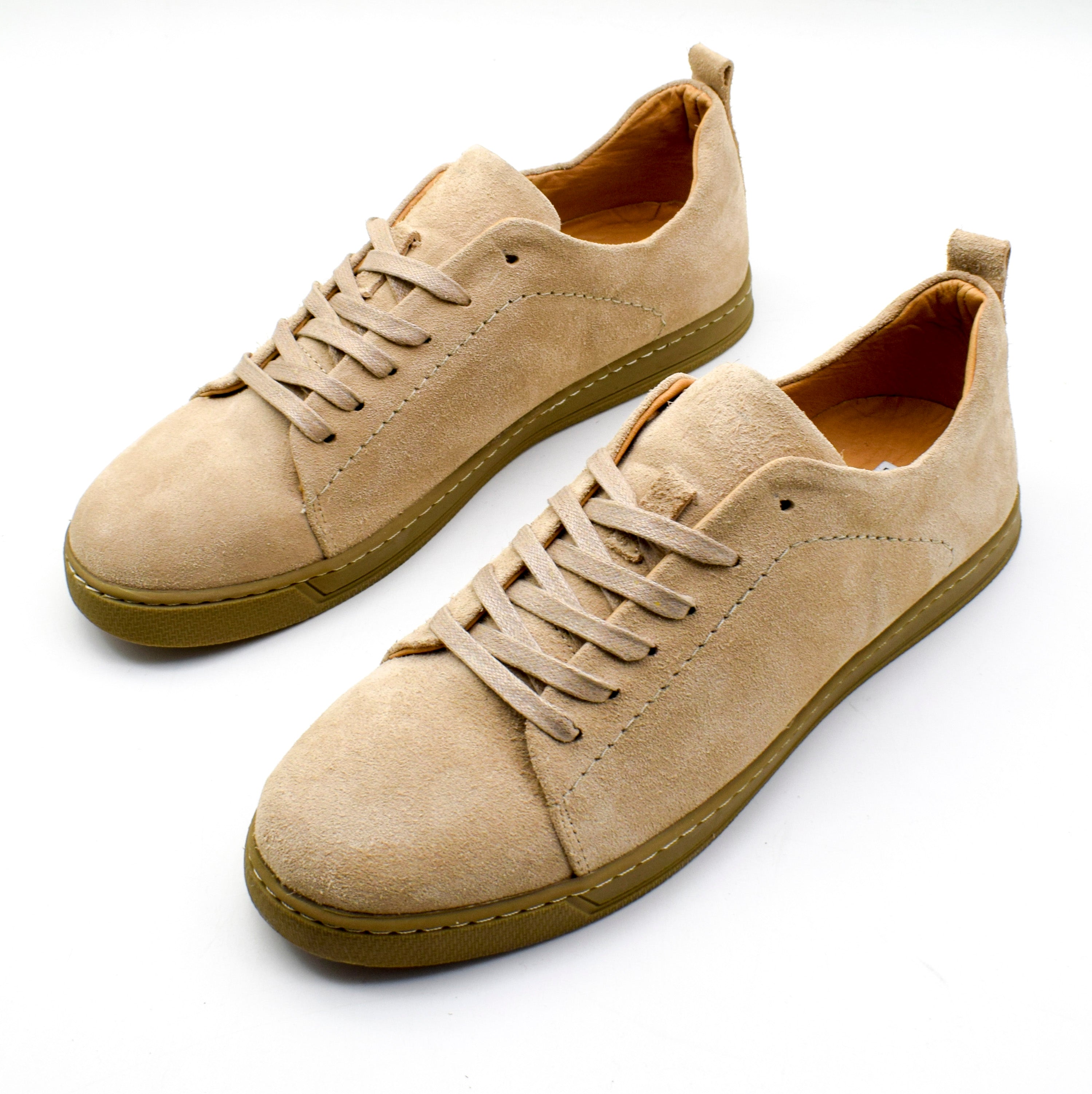 A pair of beige suede low-top sneakers with matching beige laces and olive brown soles, shown on a clean white background.