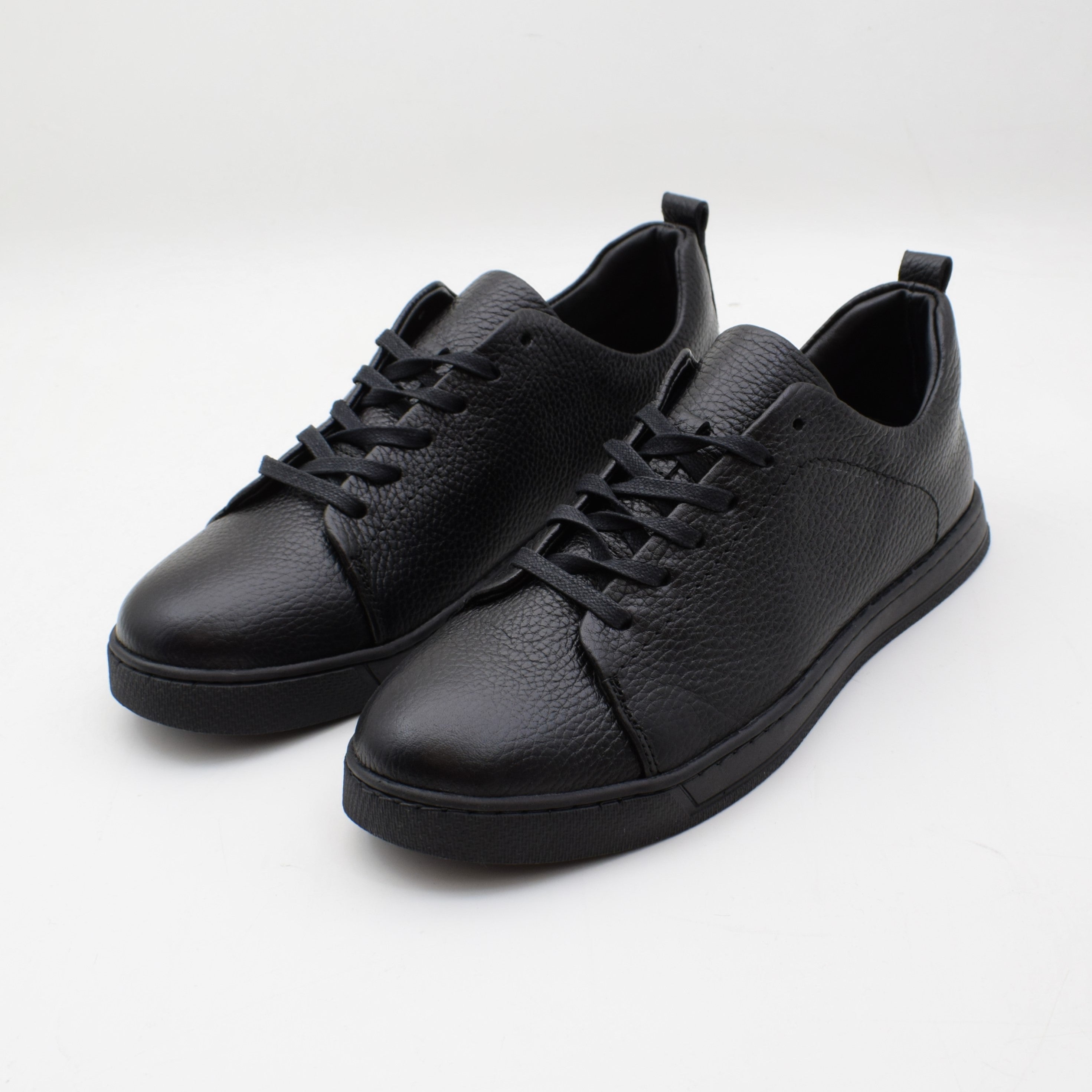 Pair of black leather sneakers on a white background