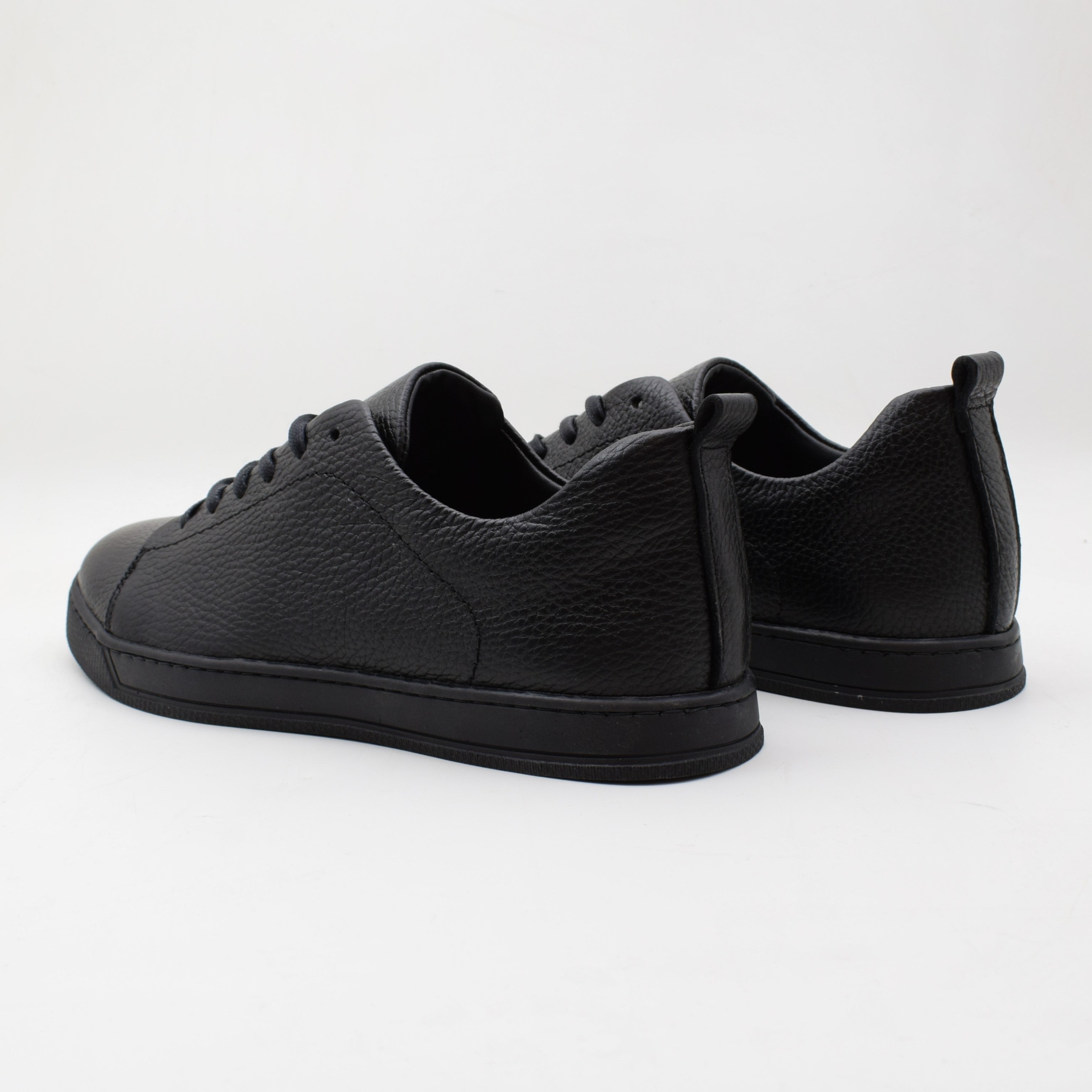 Pair of black leather sneakers on a white background