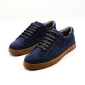 A pair of navy blue suede low-top sneakers with black laces and brown rubber soles, displayed on a clean white background.