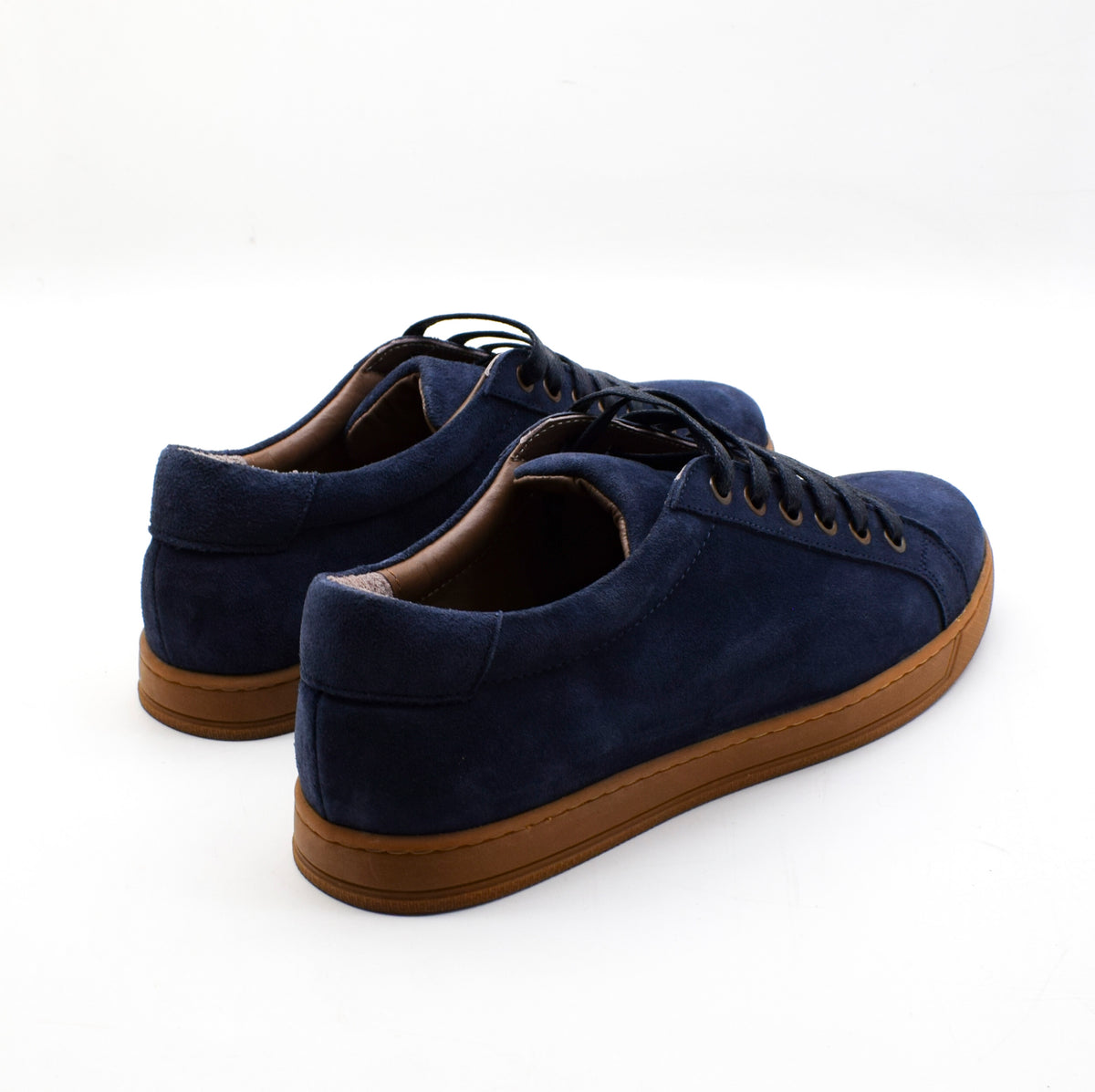 A pair of navy blue suede low-top sneakers with brown gum soles, shown from a three-quarters angle on a white background.