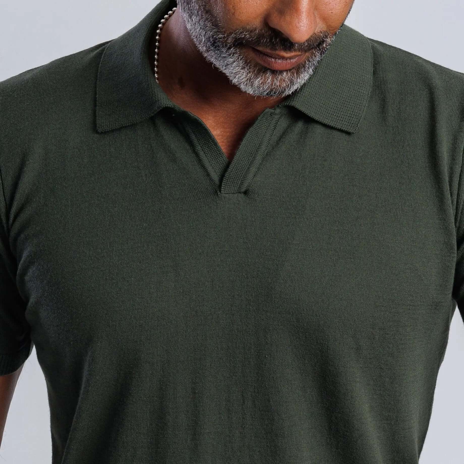 Close-up of a man wearing a green FlowKnit™ polo shirt with a classic collar, highlighting relaxed style and comfort.