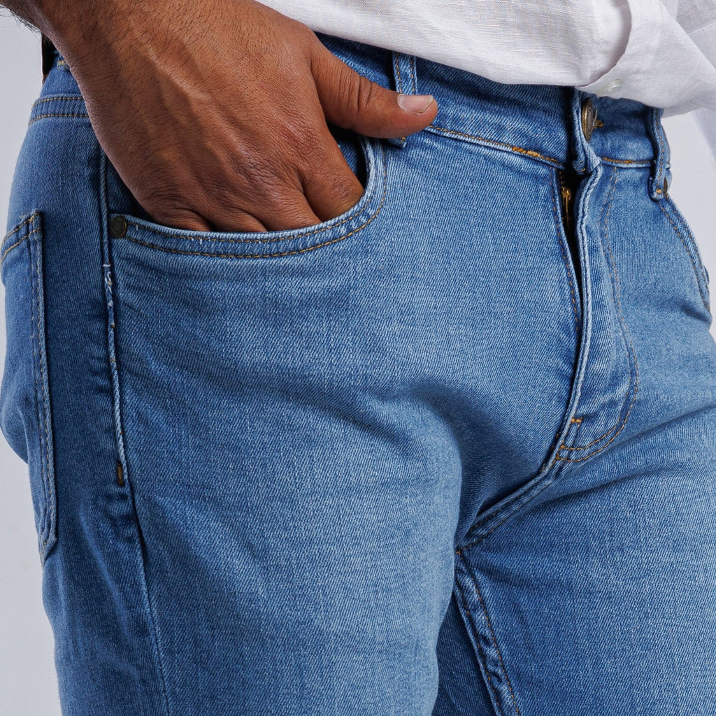 Close-up of blue jeans with a person wearing them on a light gray background
