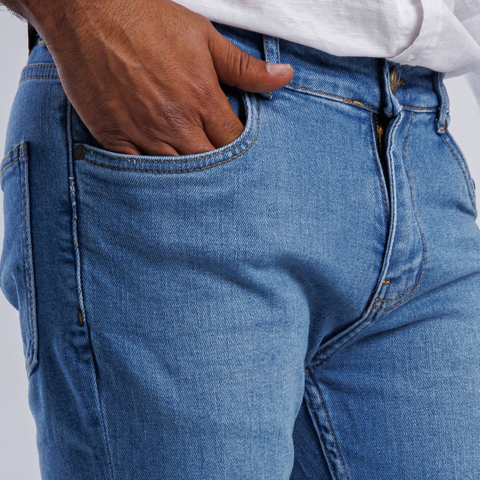 Close-up of blue jeans with a person wearing them on a light gray background