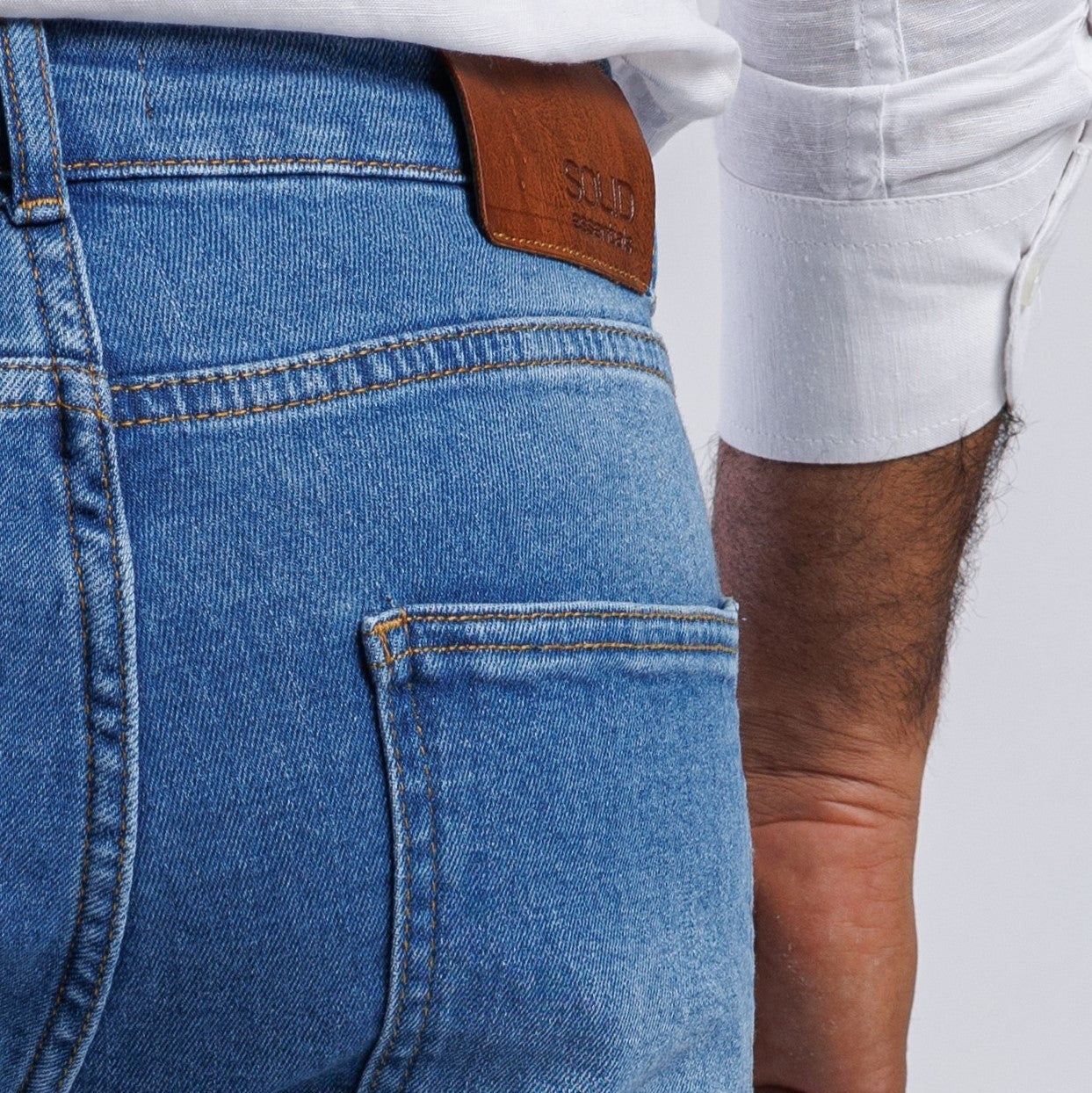 Close-up of blue jeans with a brown leather patch on a white background