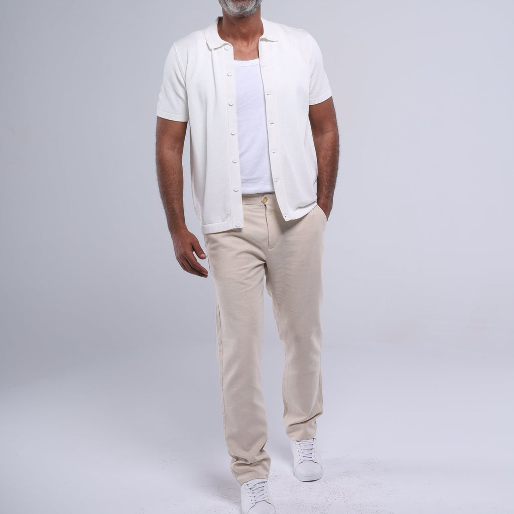 Man wearing a white shirt, beige pants, and sunglasses on a gray background
