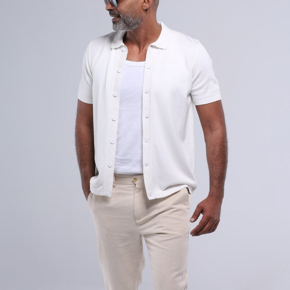 Man wearing a white shirt, beige pants, and sunglasses on a gray background