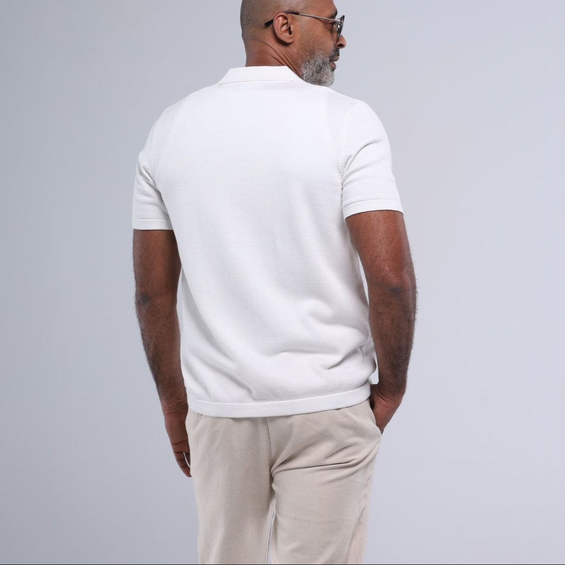 Man wearing a white t-shirt and beige pants on a gray background