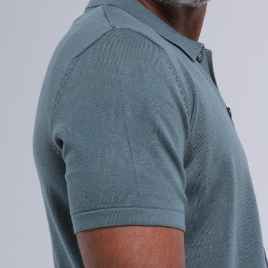 Man wearing a teal polo shirt on a light gray background