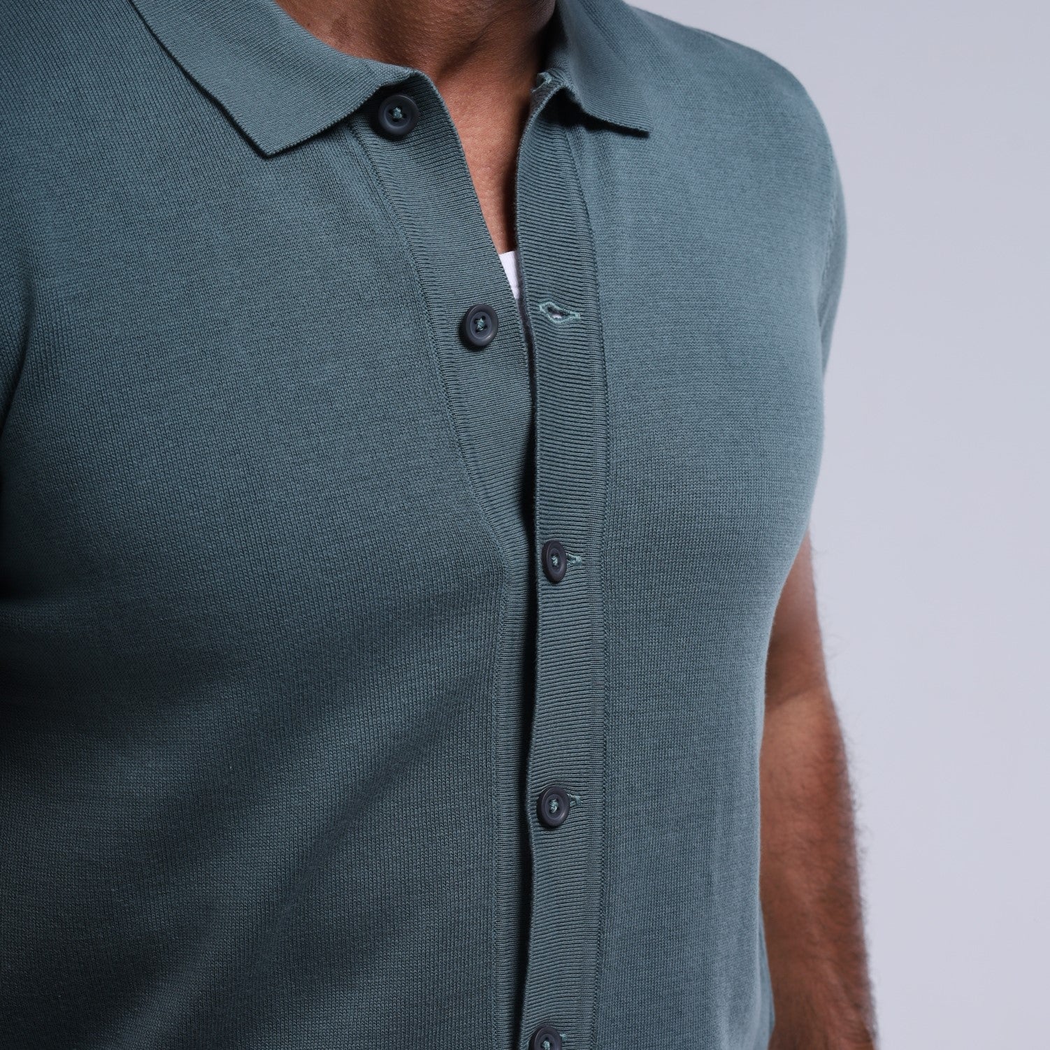 Green sleeveless button-up shirt worn by a person on a plain background