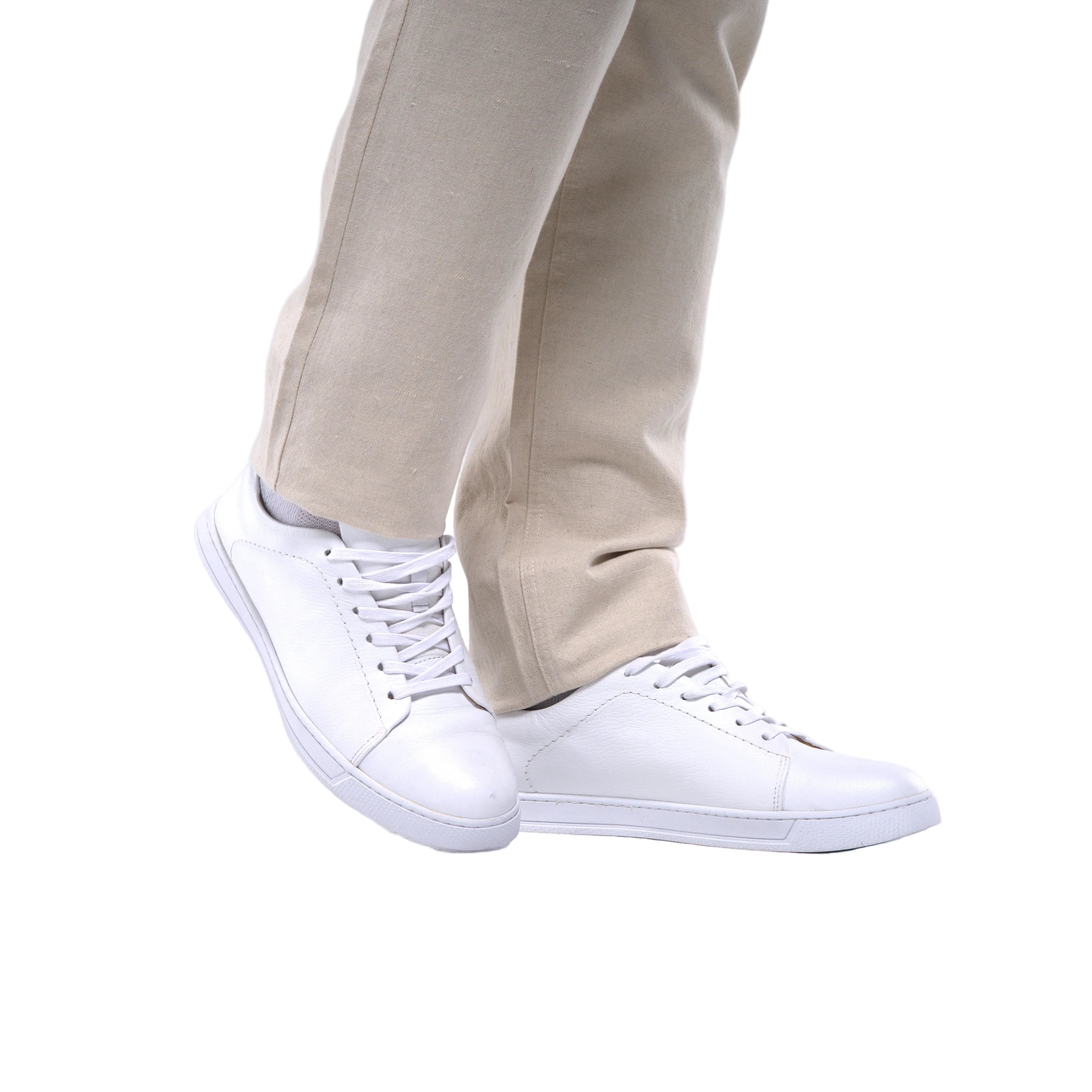 White sneakers worn with beige pants on a white background