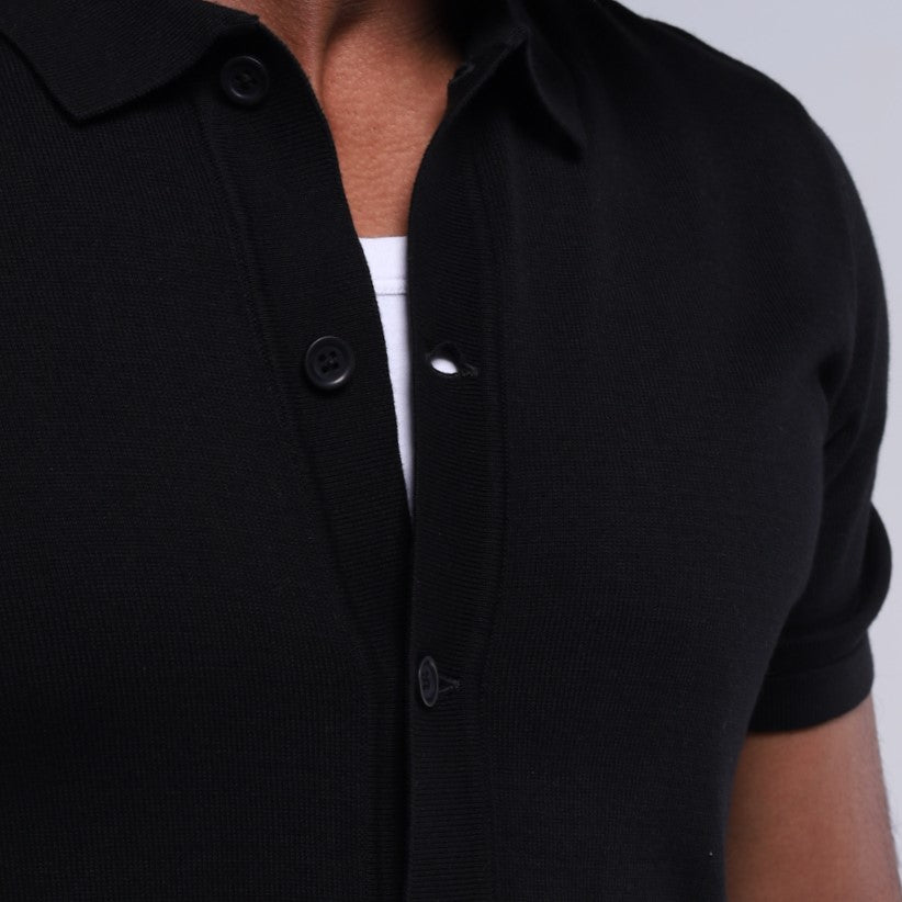 Black short-sleeve shirt with buttons on a plain background