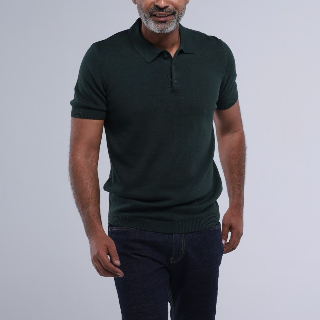 Man wearing a dark green polo shirt against a light gray background