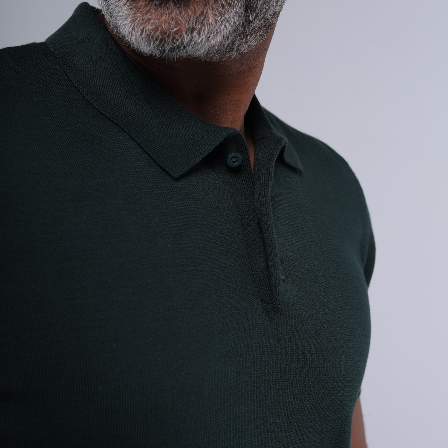 Man wearing a dark green polo shirt against a plain background