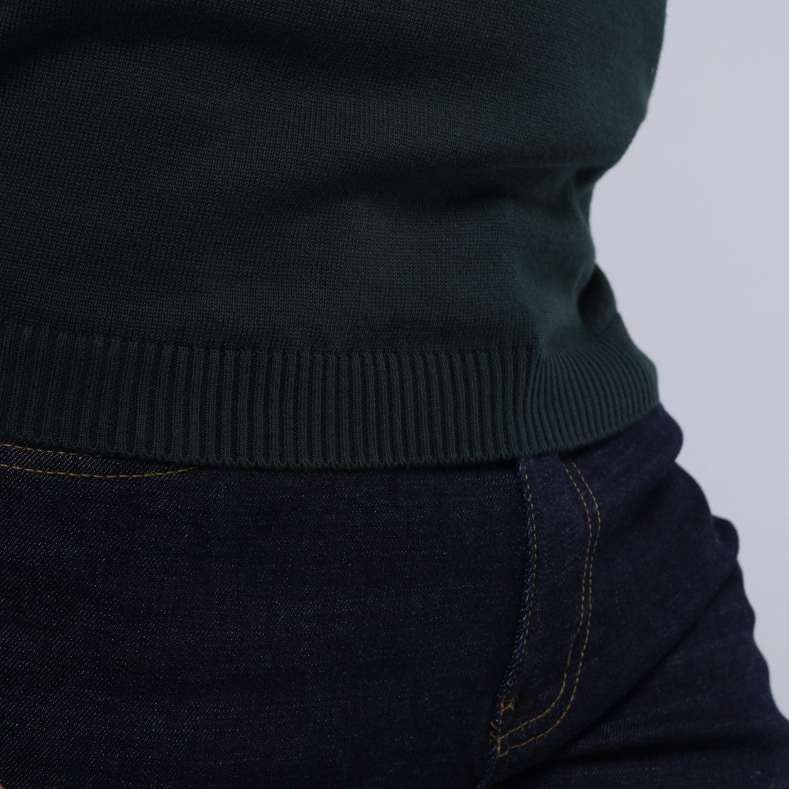 Dark green sweater and dark jeans on a light gray background