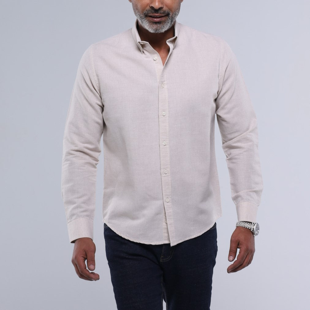 Man wearing a light-colored button-up shirt and dark pants on a plain background