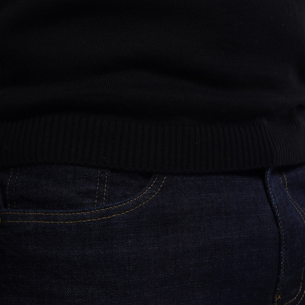 Close-up of a black sweater and dark jeans with visible stitching.