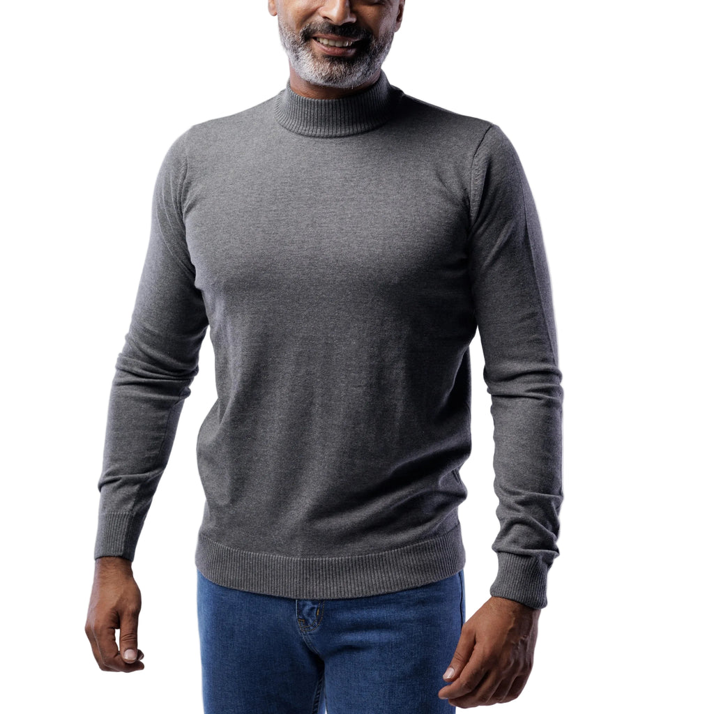 Man wearing a gray turtleneck sweater and blue jeans on a light gray background