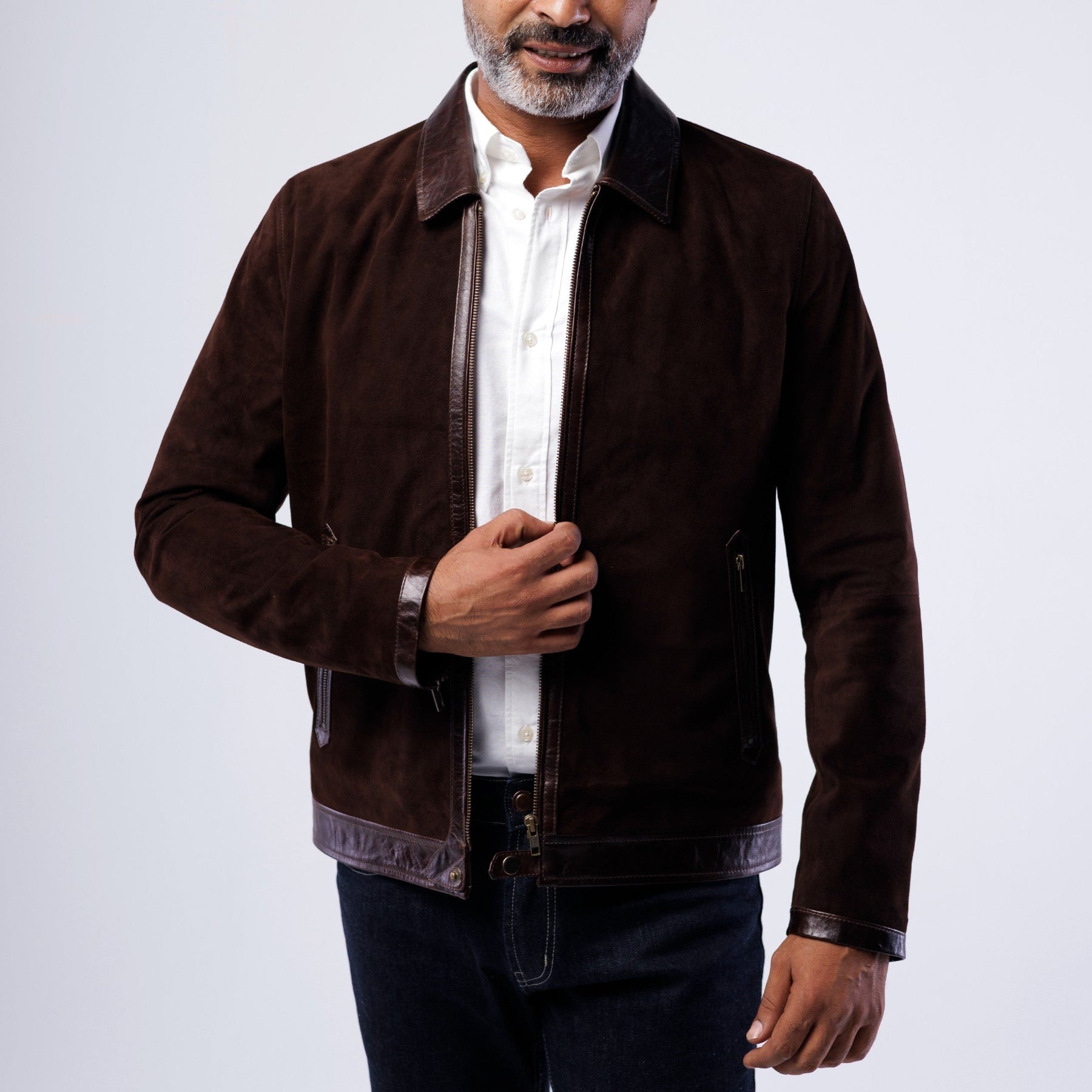 Man wearing a brown jacket over a white shirt on a white background
