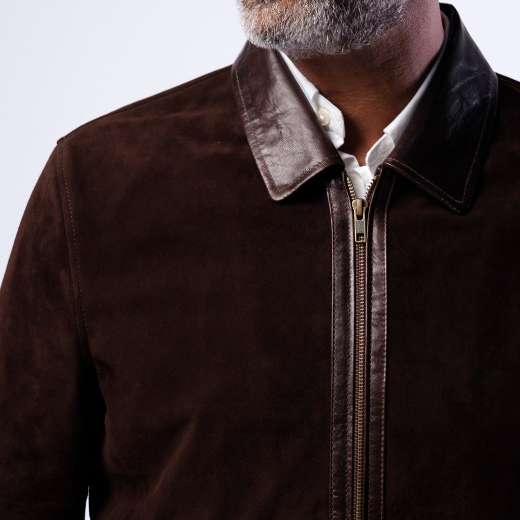 Brown jacket with leather collar worn by a person on a light gray background