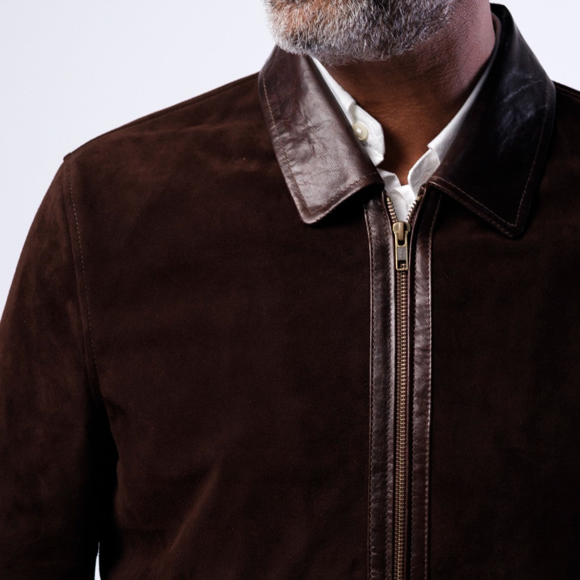 Brown jacket with leather collar worn by a person on a light gray background