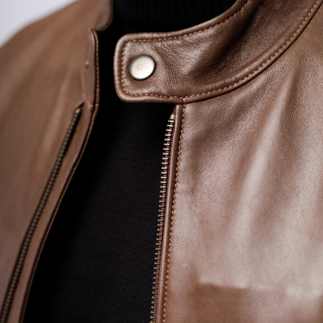 Close-up of a brown leather jacket with a zipper