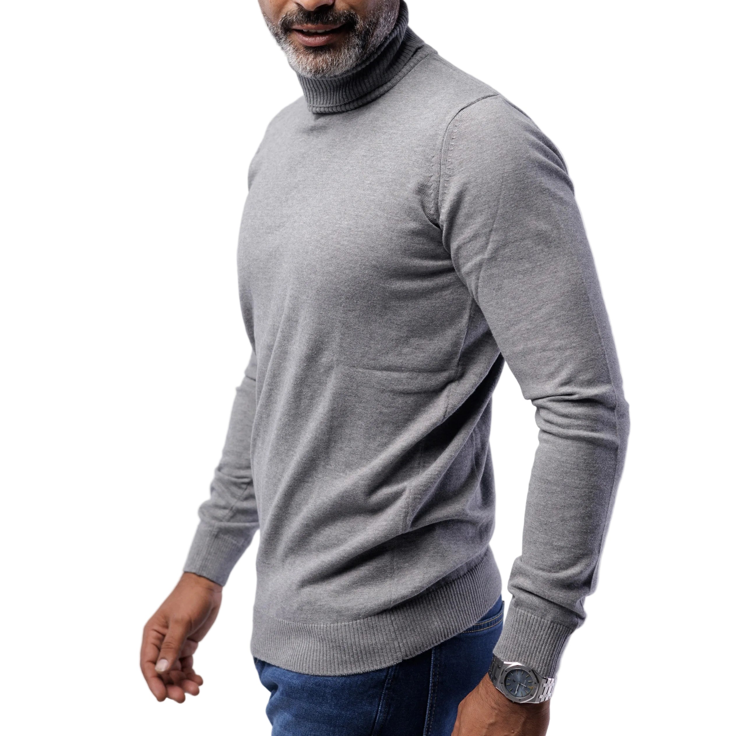 Man wearing a gray turtleneck sweater and blue jeans on a light gray background