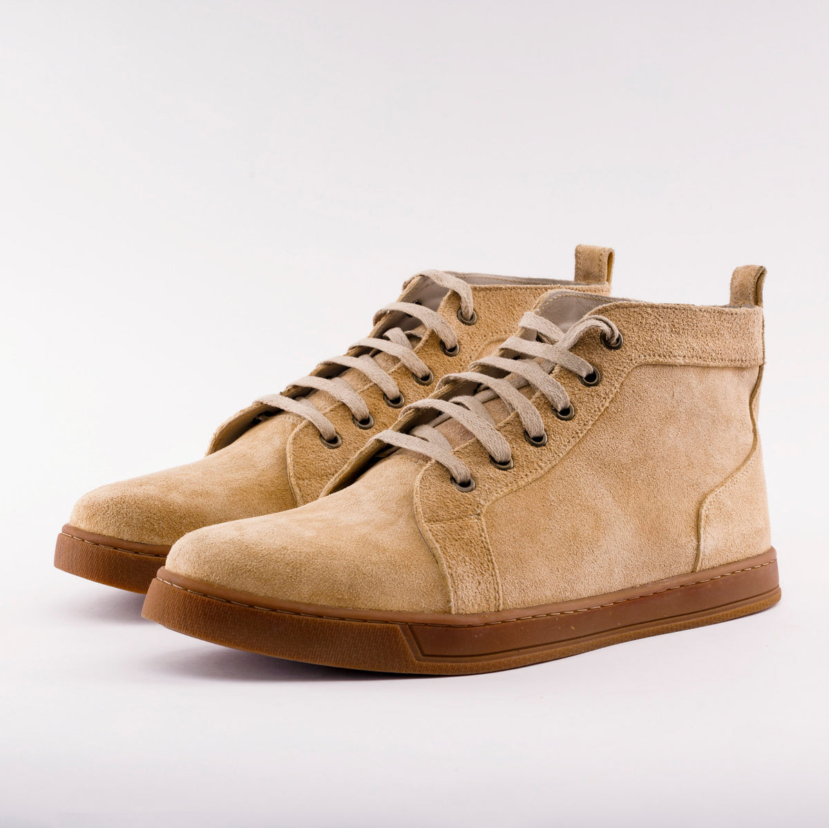A pair of beige suede high-top sneakers with brown soles, displayed on a clean white background.