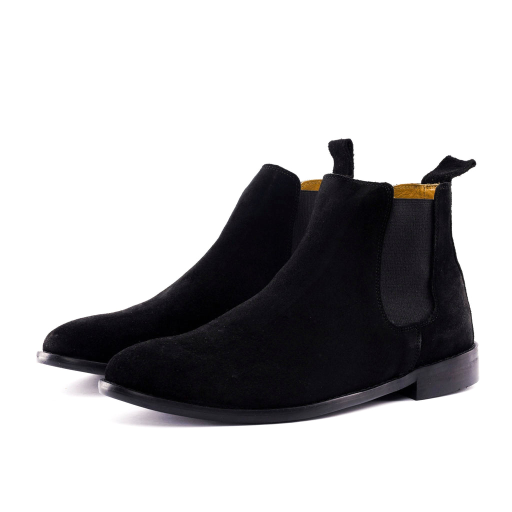 A pair of black suede Chelsea boots with black elastic side panels, shown from a side profile view on a clean white background.