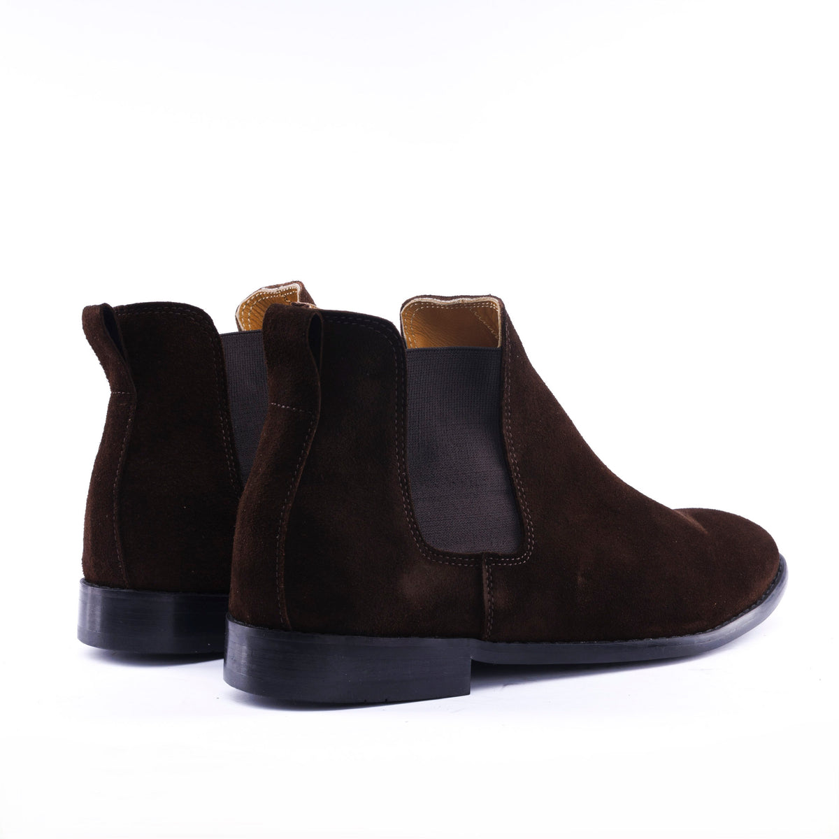 A pair of dark brown suede Chelsea boots with black elastic side panels and black soles, shown from a rear three-quarter angle on a white background.