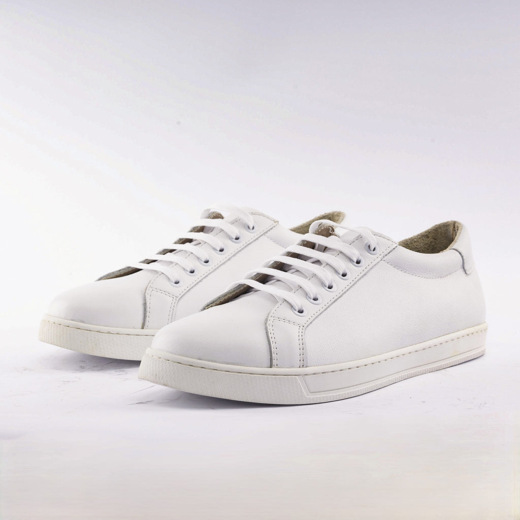 A pair of white leather low-top sneakers with white laces and white soles, photographed on a clean white studio background.