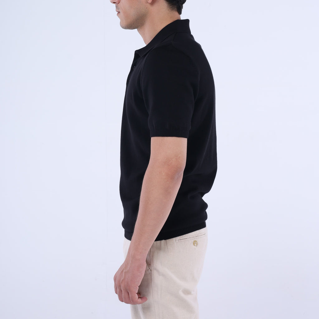 Person wearing a black polo shirt and beige pants on a light gray background