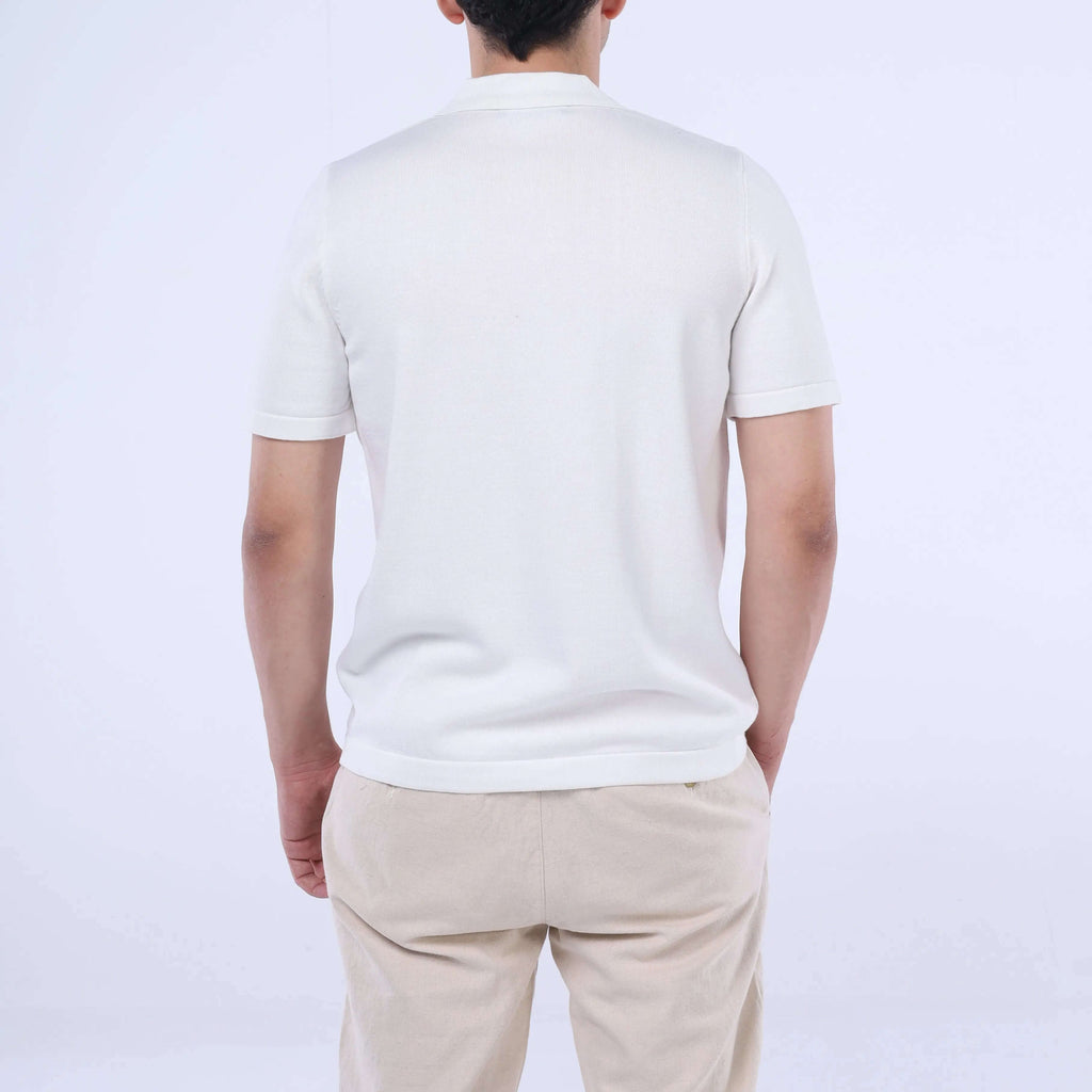Back view of a man wearing a solid Knit-Layer™ Short Sleeve Shirt in white, paired with beige pants.