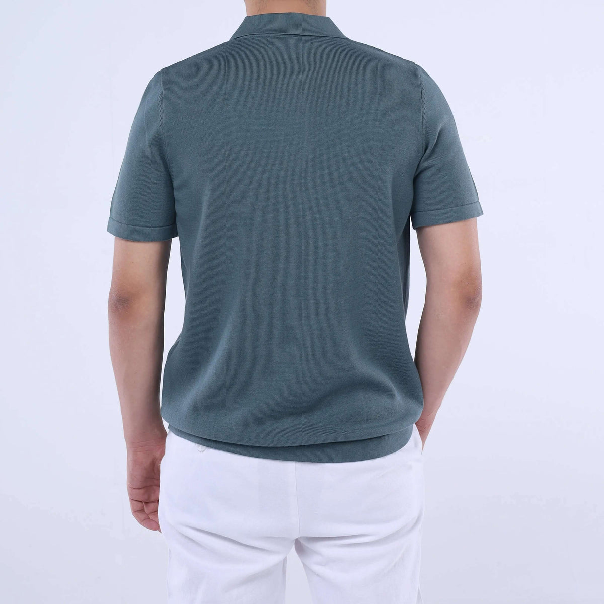 Back view of a man wearing a Knit-Layer™ Short Sleeve Shirt in green, showcasing its versatile design and lightweight fabric.
