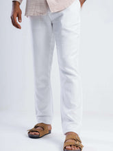 Load image into Gallery viewer, Model wearing white linen blend tapered trousers, styled with a light shirt and sandals, showcasing a tailored fit.
