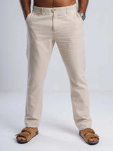 Load image into Gallery viewer, Beige linen blend tapered trousers with tailored fit, featuring side pockets and YKK zip fly, styled with sandals.
