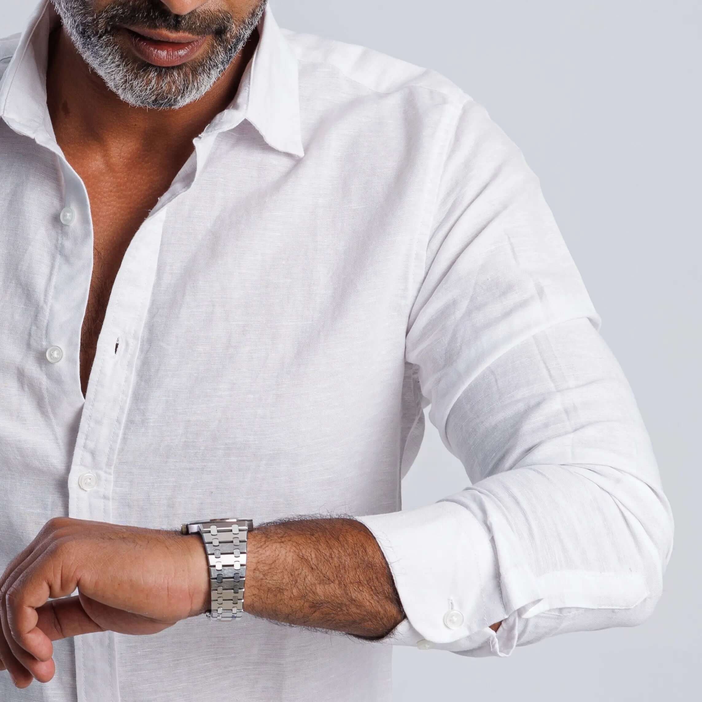 Man in a white linen blend slim fit shirt checking his watch, showcasing breathable comfort and elegance.