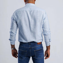 Load image into Gallery viewer, Back view of a man wearing a light blue linen blend slim fit shirt with long sleeves and casual jeans.
